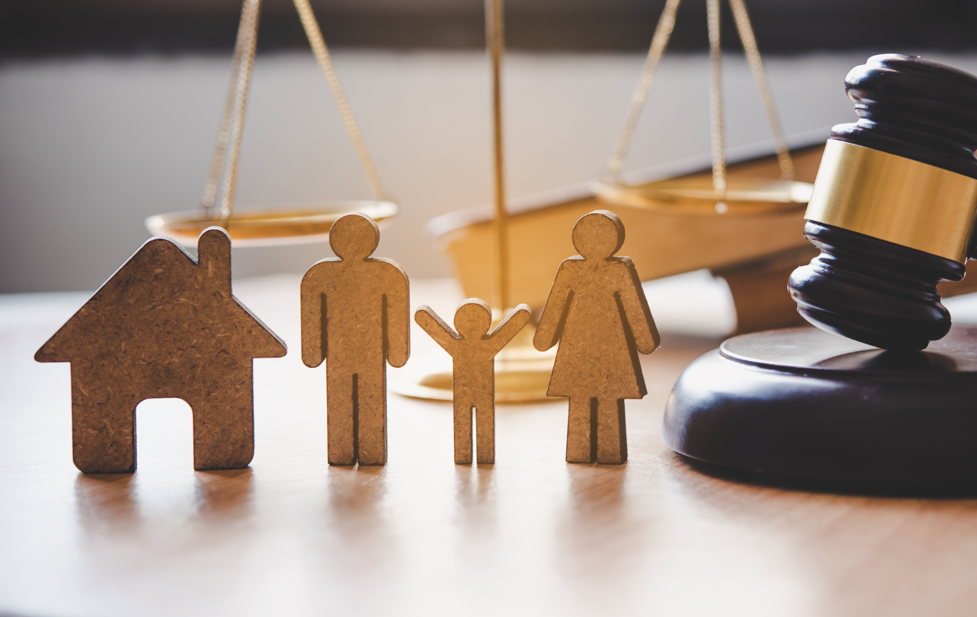 Wooden family figures, house, scales, and gavel symbolizing family law and justice.