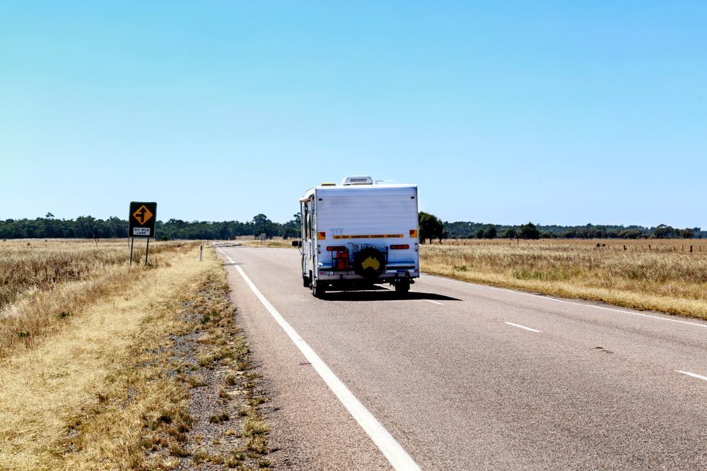 Campervan Traveling on A Rural Road Under a Clear Blue Sky — Centre Trailer Sales In Alice Springs, NT