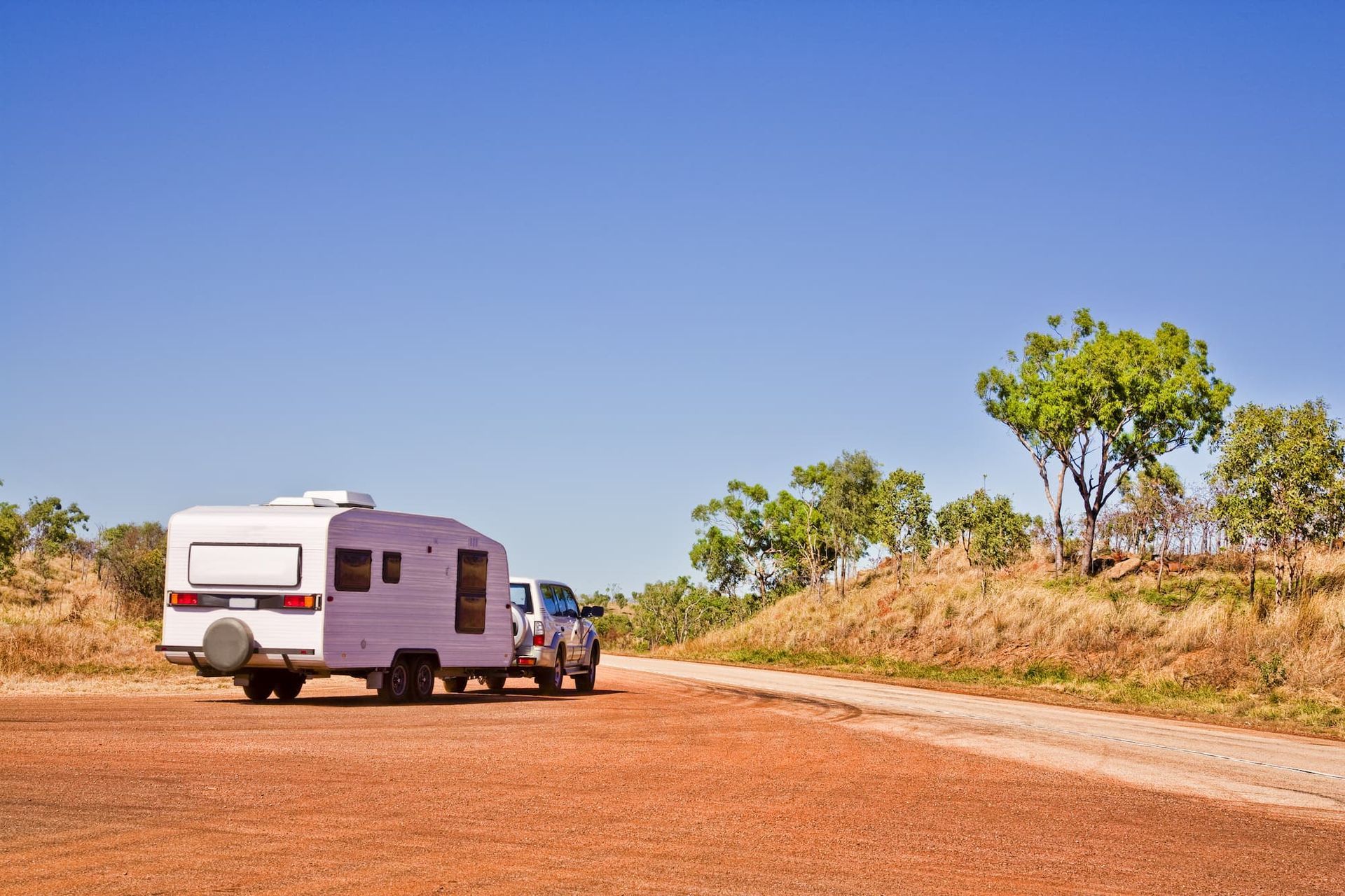 White Camper Trailer Hitched to A Truck on A Red Dirt Road — Centre Trailer Sales In Alice Springs, NT