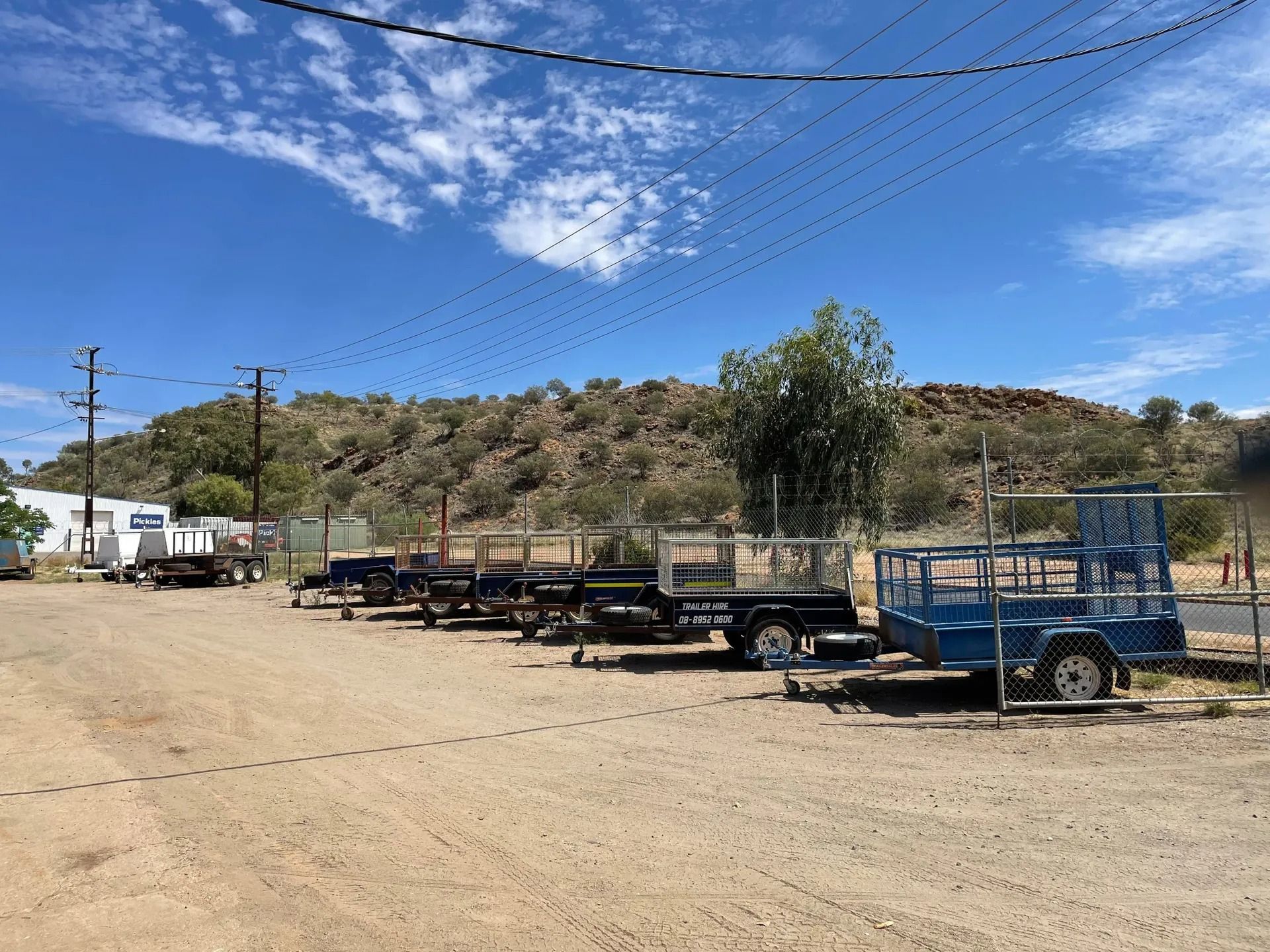 A Row of Trailers Parked on A Dirt Lot with A Hill in The Background — Centre Trailer Sales In Alice Springs, NT