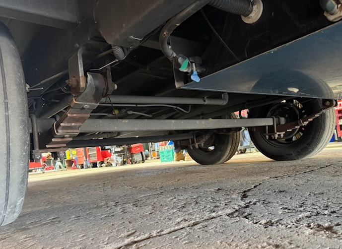 Underside of a vehicle showing axles, leaf springs, and wheels against a gray concrete surface. — Centre Trailer Sales In Alice Springs, NT