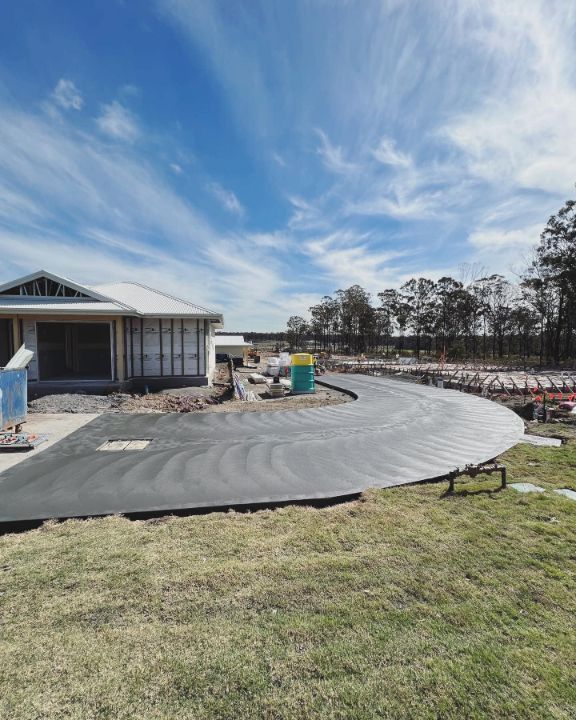 A Concrete Driveway is Being Built in Front of a House — Coastal Kerb and Concrete In Buff Point, NSW