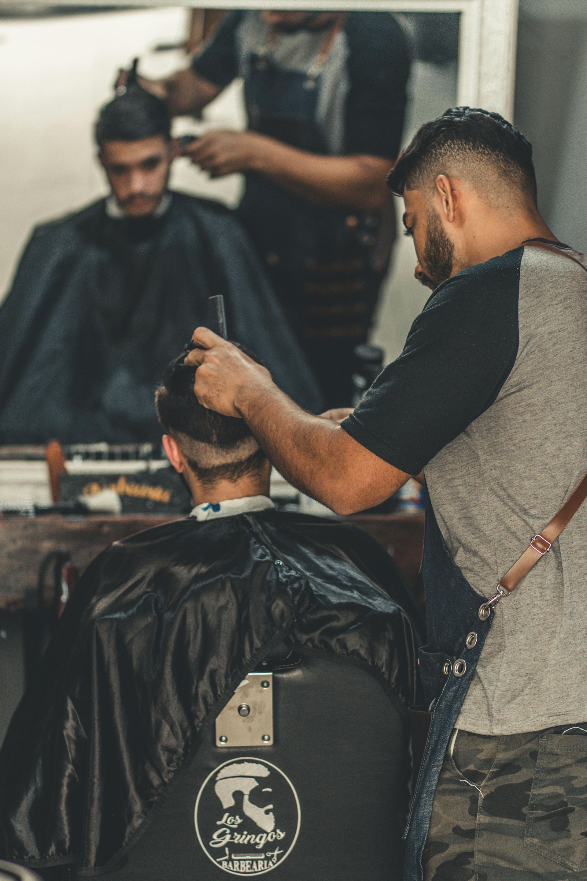 Hairdresser cutting wet, dark hair with scissors and comb.
