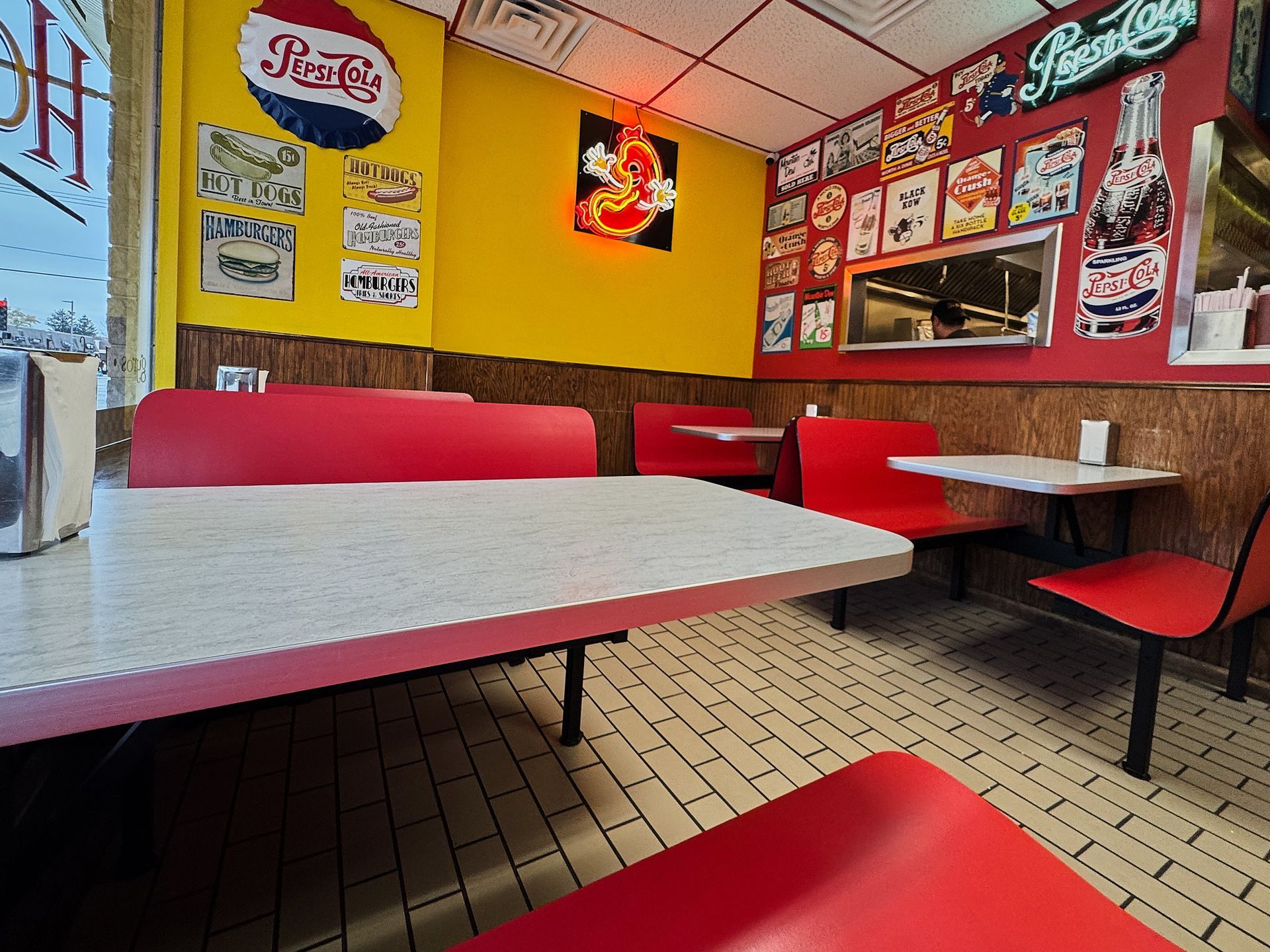 Interior of a retro diner with red booths, yellow walls, and vintage Pepsi signage.