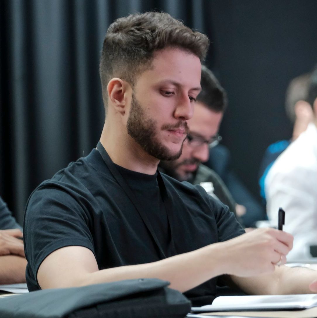 Um homem com barba está escrevendo em um caderno