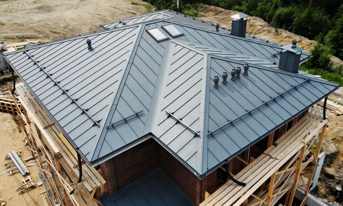 Gray metal roof on a house under construction, viewed from above with scaffolding around the edges
