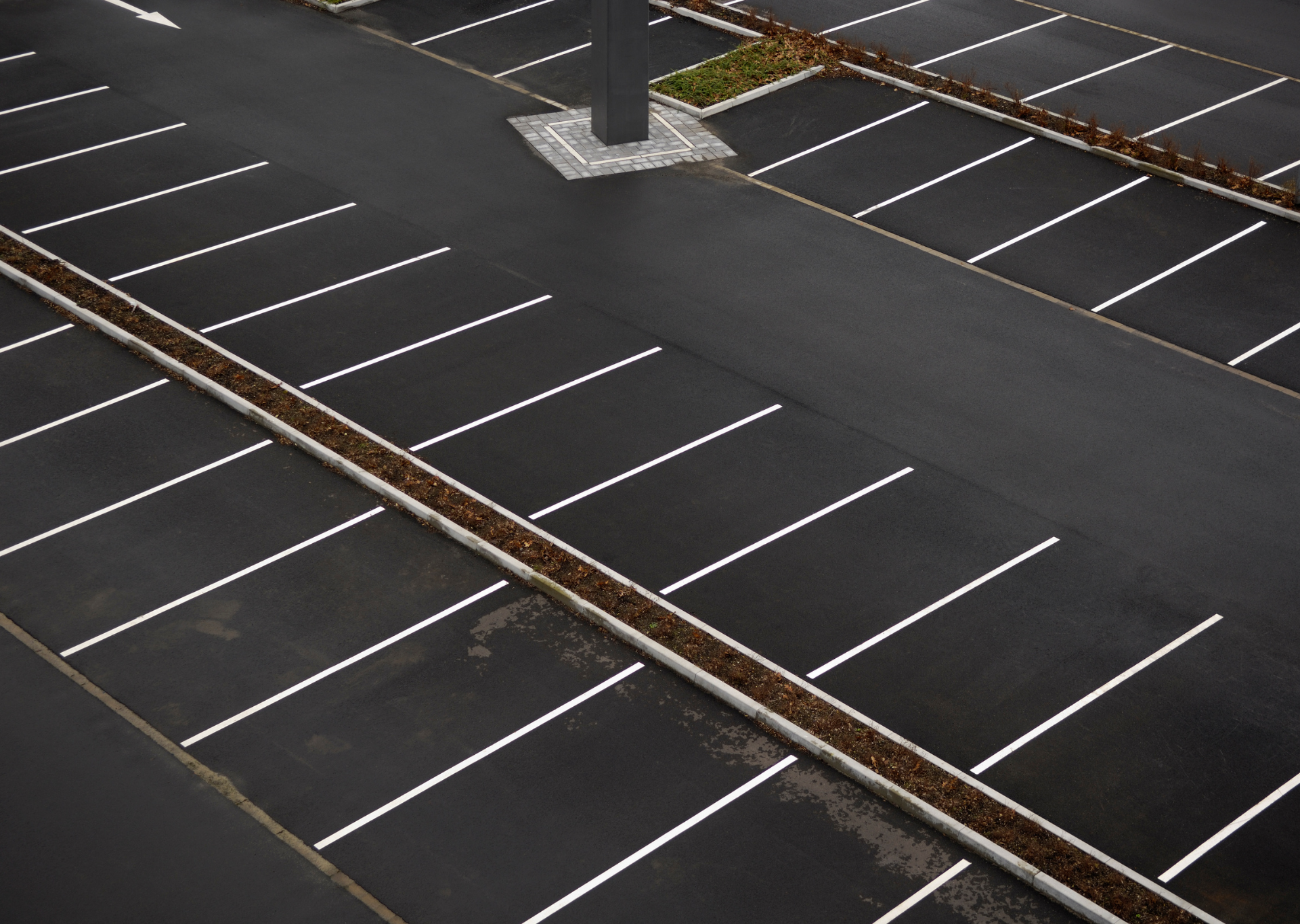Empty black asphalt parking lot with white parking space lines.