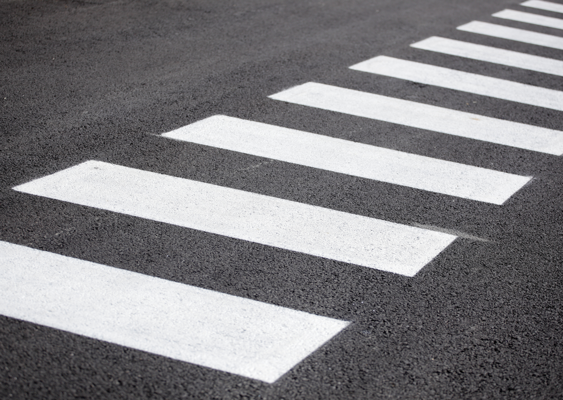 Crosswalk on asphalt road, white stripes, black background.