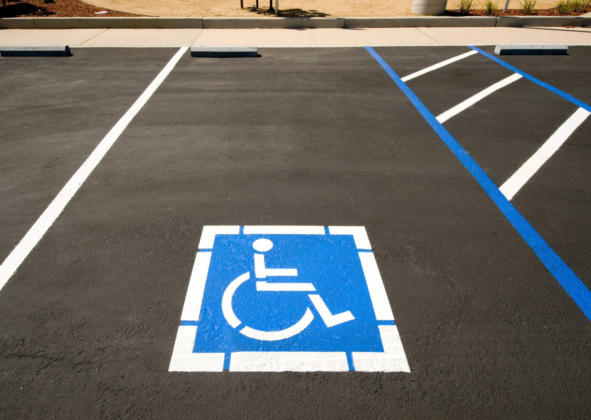 Blue and white handicap parking space in asphalt parking lot.