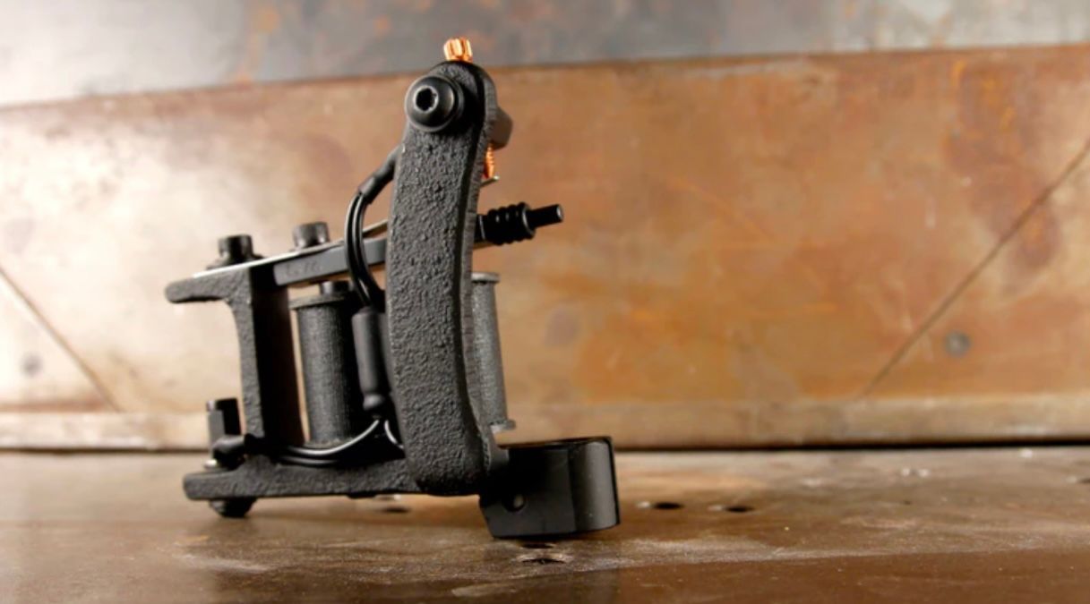 A black tattoo machine is sitting on a wooden table.