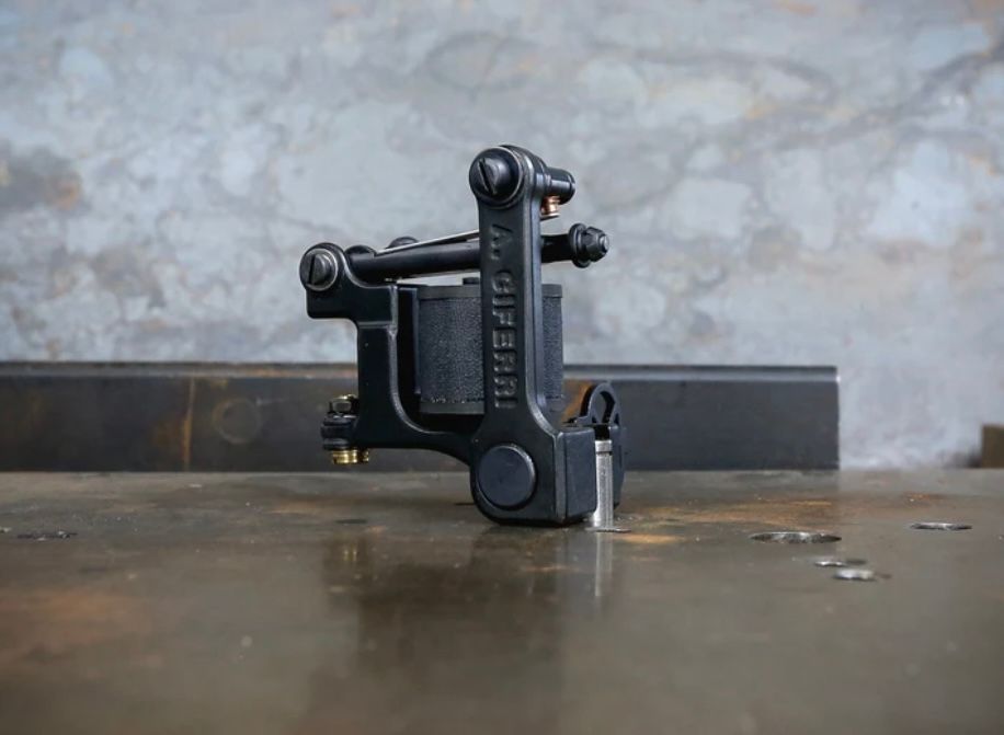 A black tattoo machine is sitting on a table.