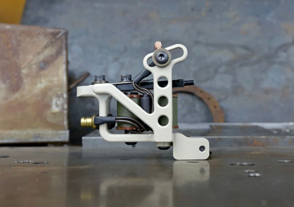 A white tattoo machine is sitting on a table.
