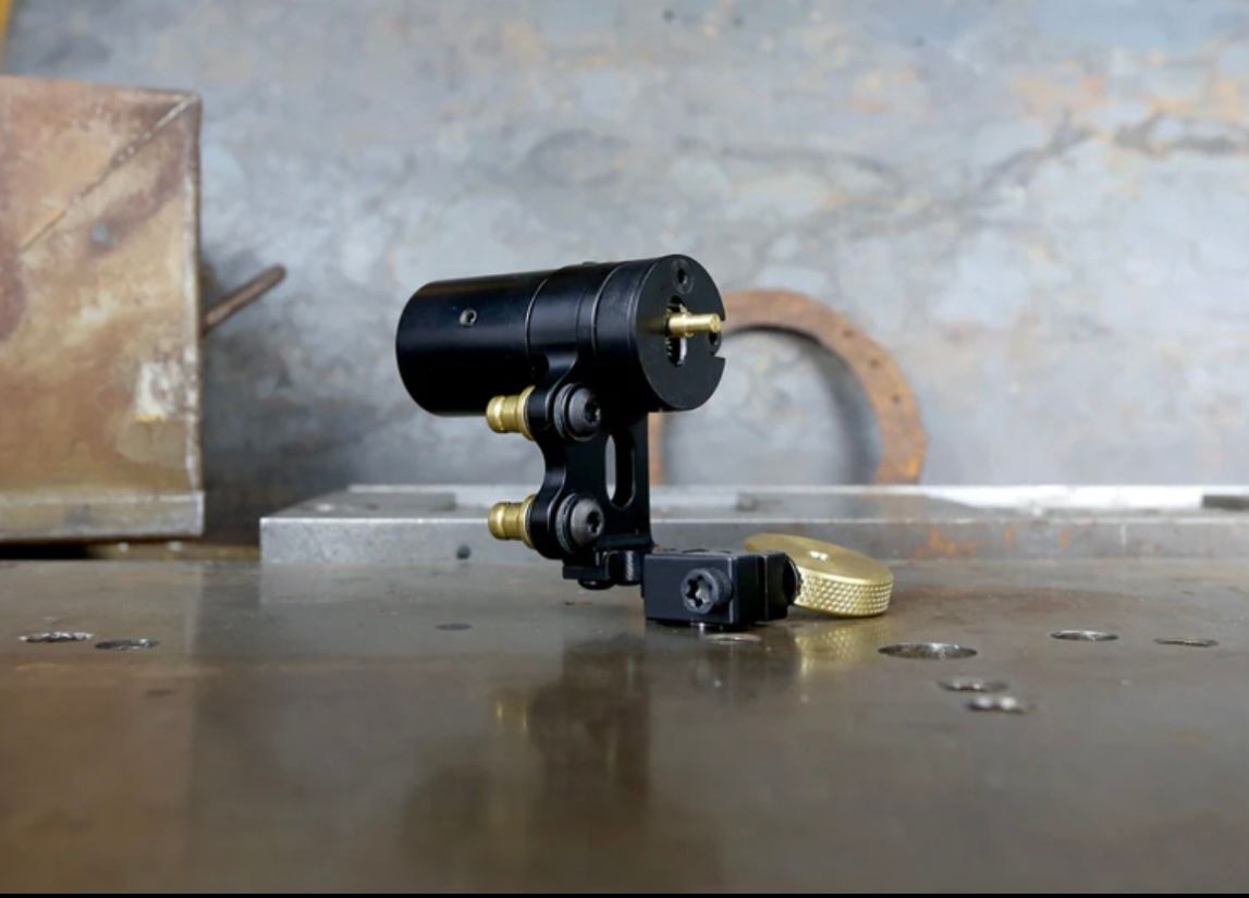 A black tattoo machine is sitting on a wooden table.