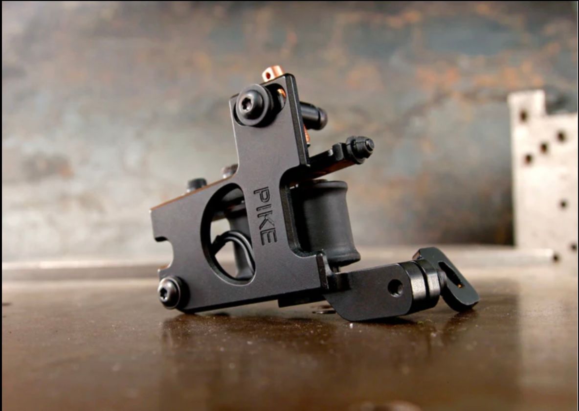 A black tattoo machine is sitting on a wooden table.