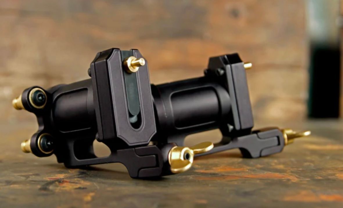 A black tattoo machine is sitting on a wooden table.