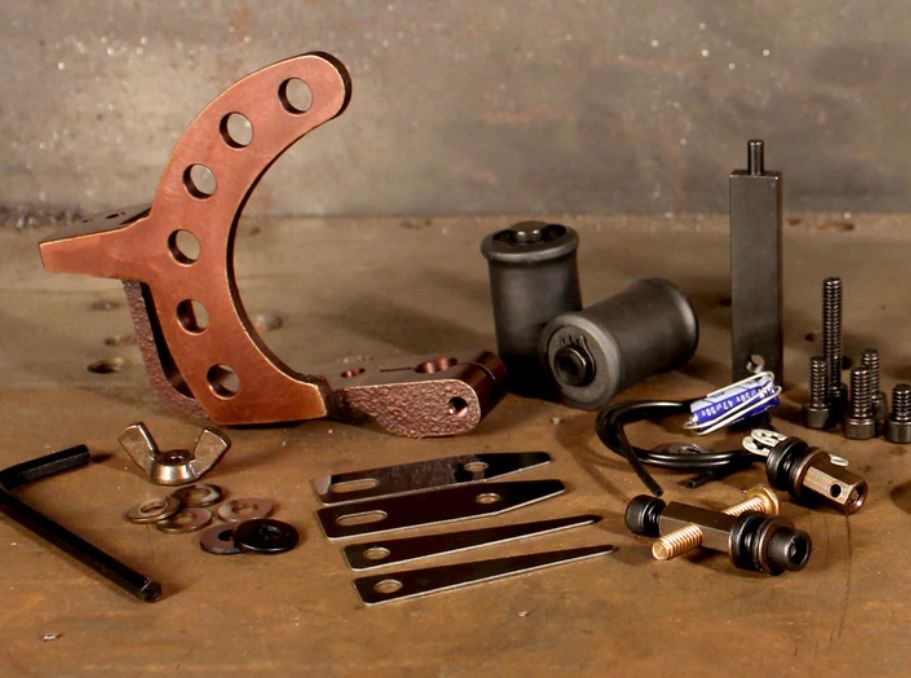 A bunch of tools are on a table including a tattoo machine
