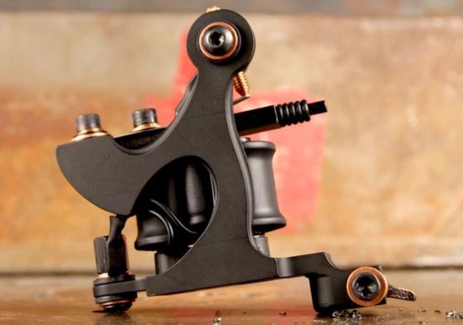 A black tattoo machine is sitting on a wooden table.