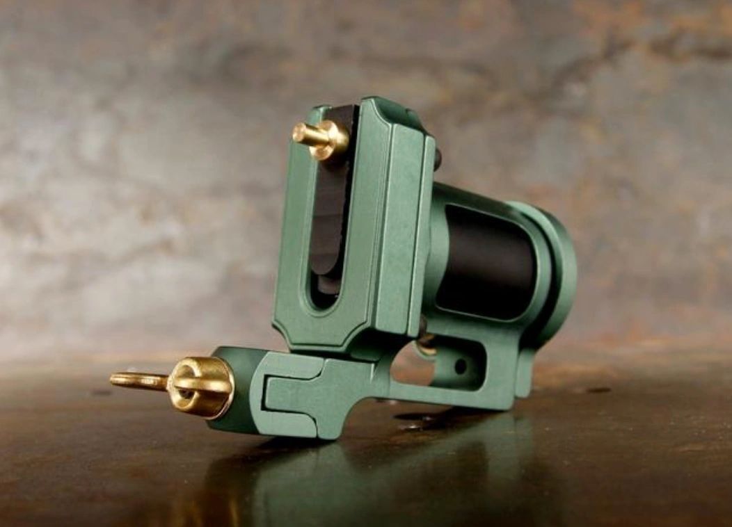 A green tattoo machine is sitting on a wooden table.