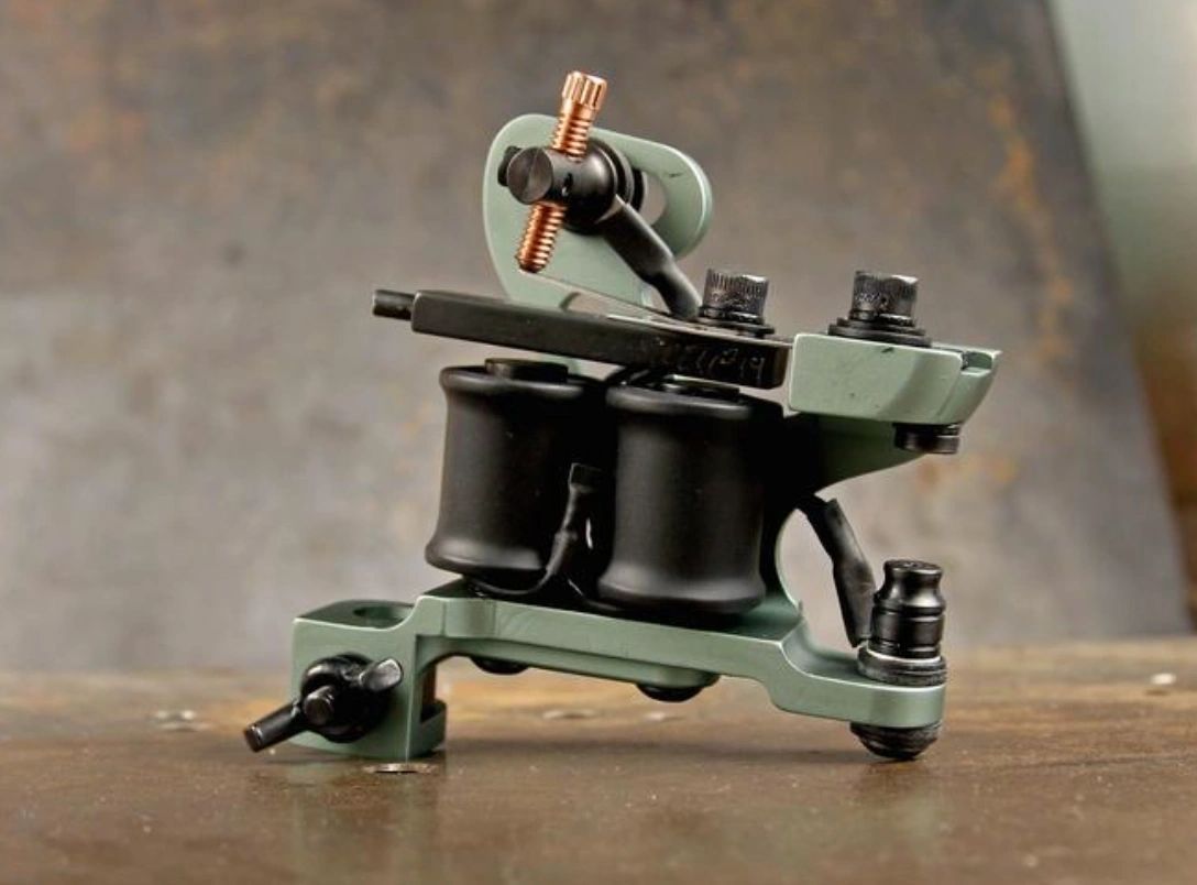 A green tattoo machine is sitting on a wooden table.