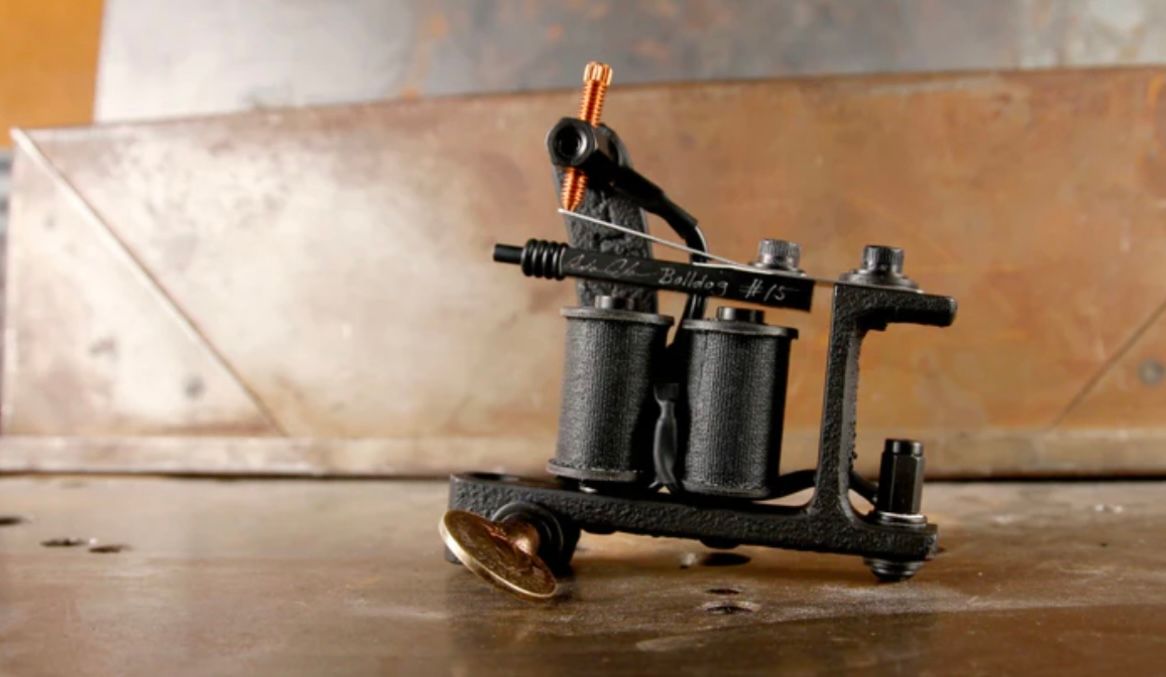 A black tattoo machine is sitting on a wooden table.