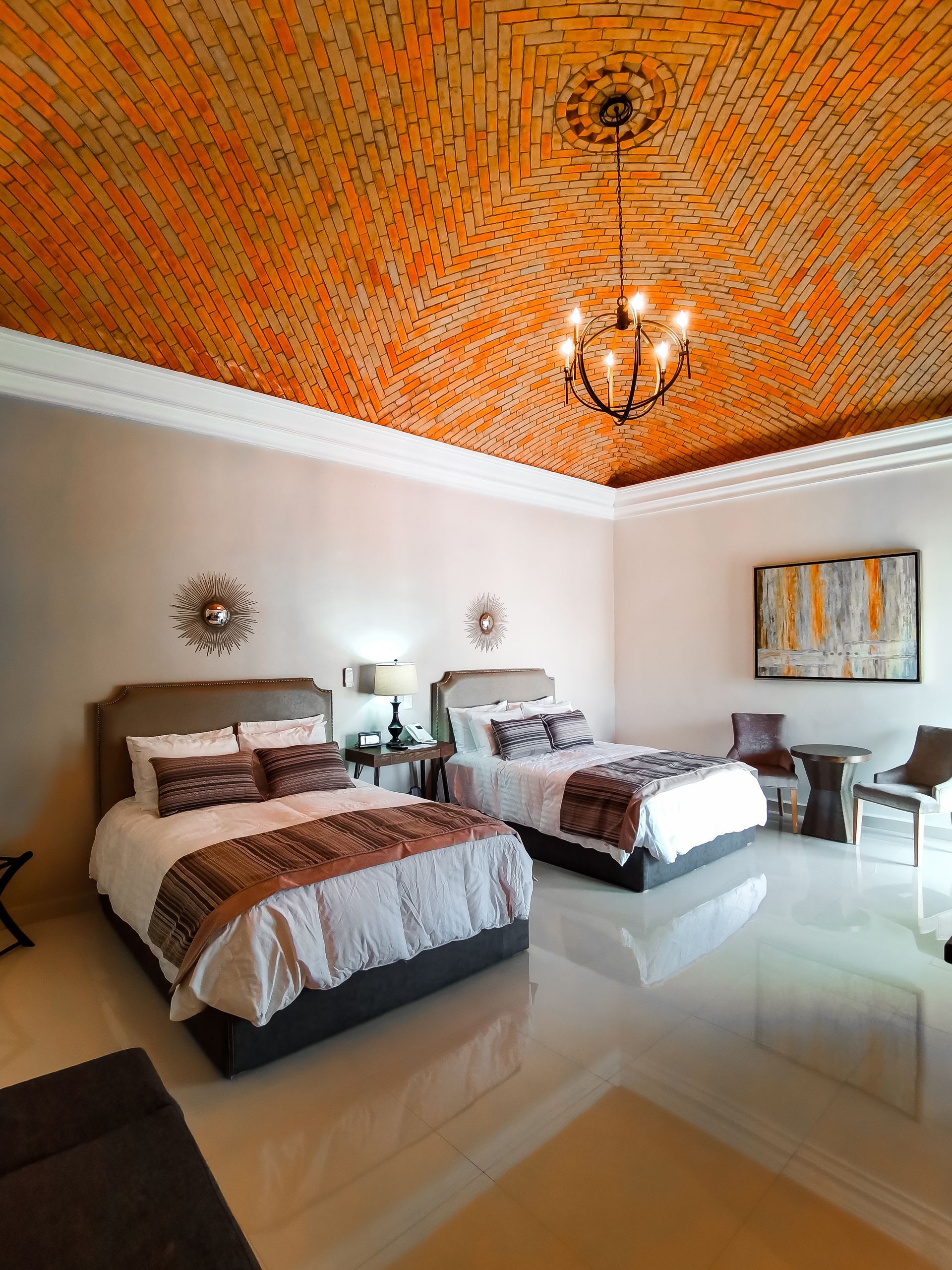 Una habitación de hotel con dos camas y una lámpara de araña.