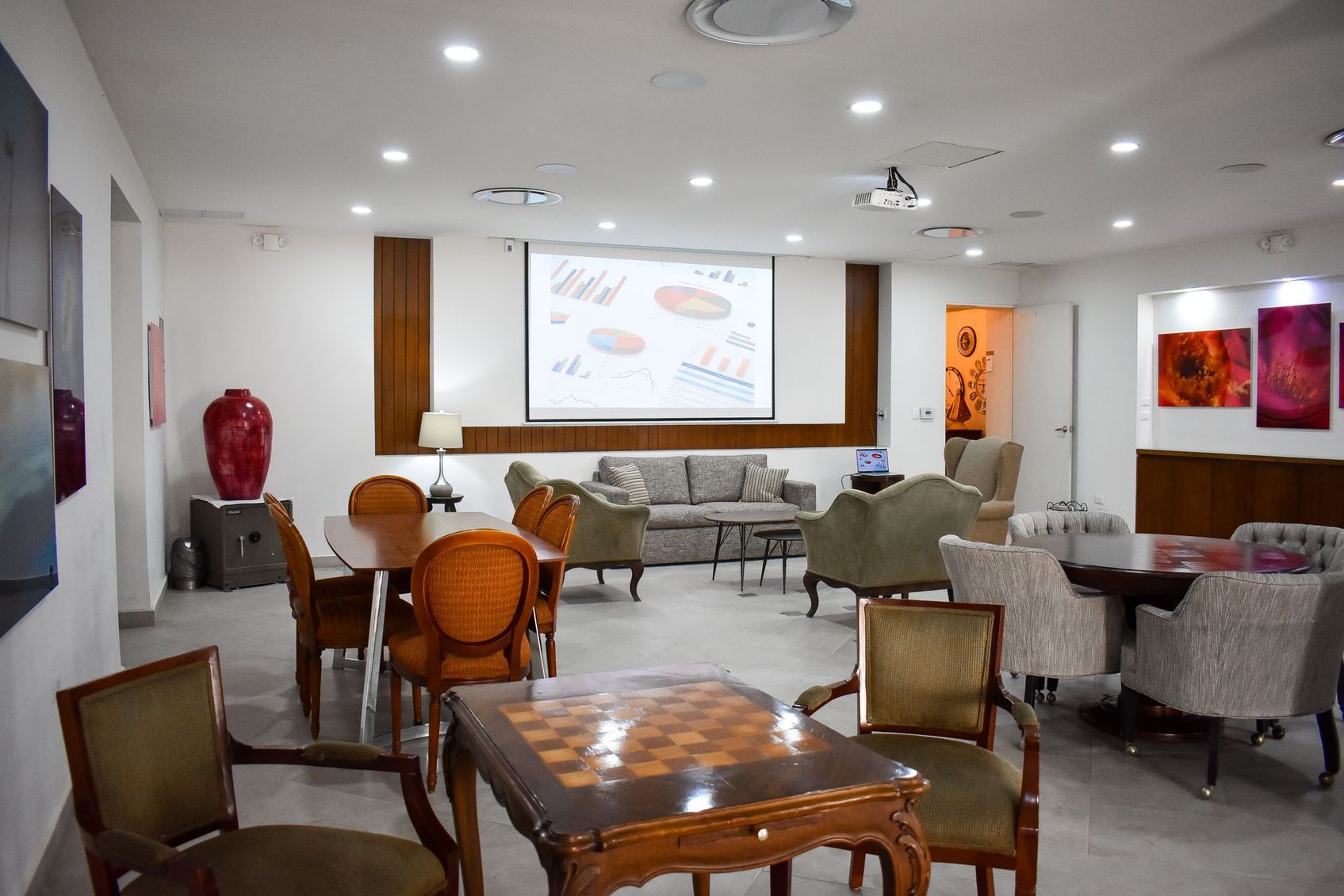 Una sala grande con pantalla de proyector, mesas, sillas y un tablero de ajedrez.