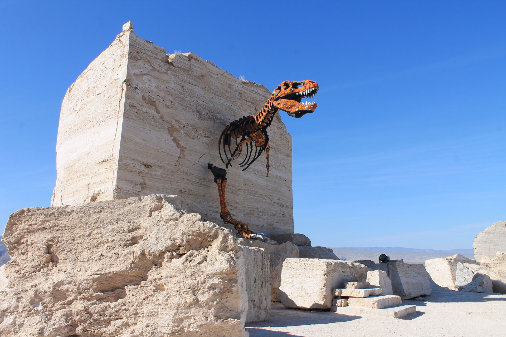 A statue of a dinosaur is sitting on top of a large rock.