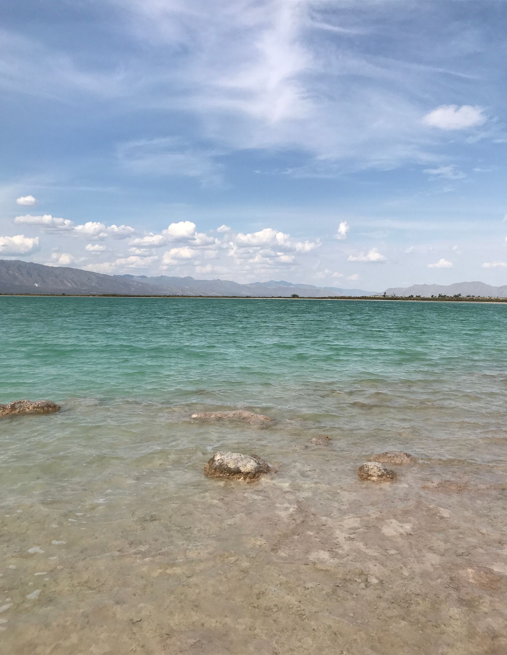 A large body of water with mountains in the background on a sunny day.