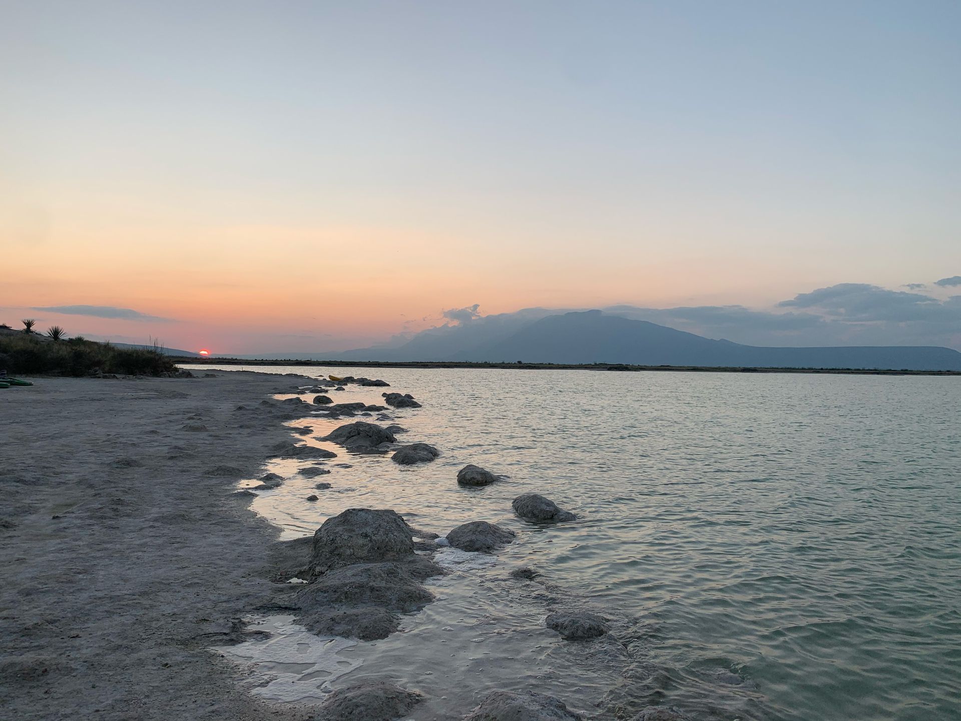 A sunset over a body of water with mountains in the background