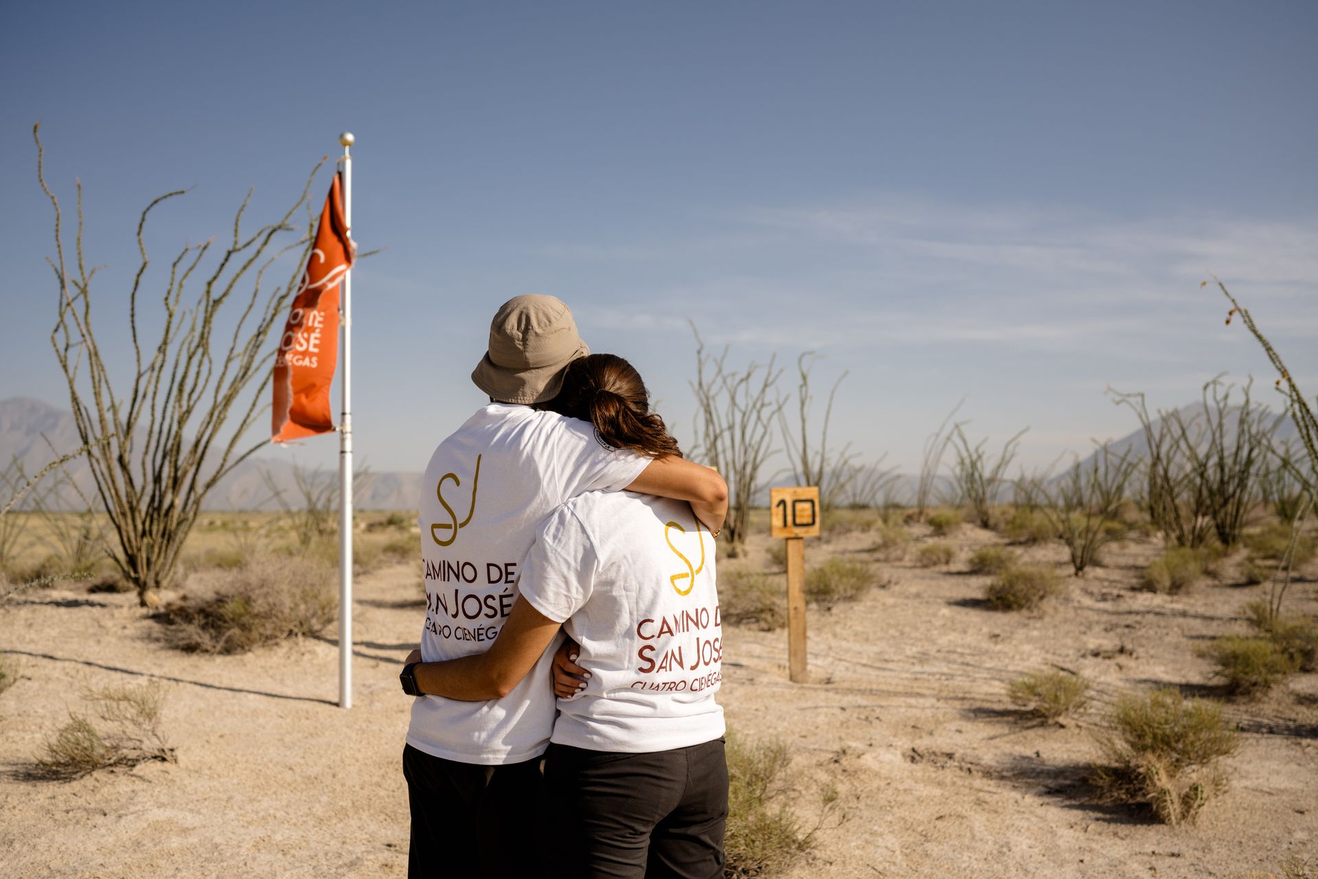 Un hombre y una mujer se abrazan frente a un cartel que dice 10