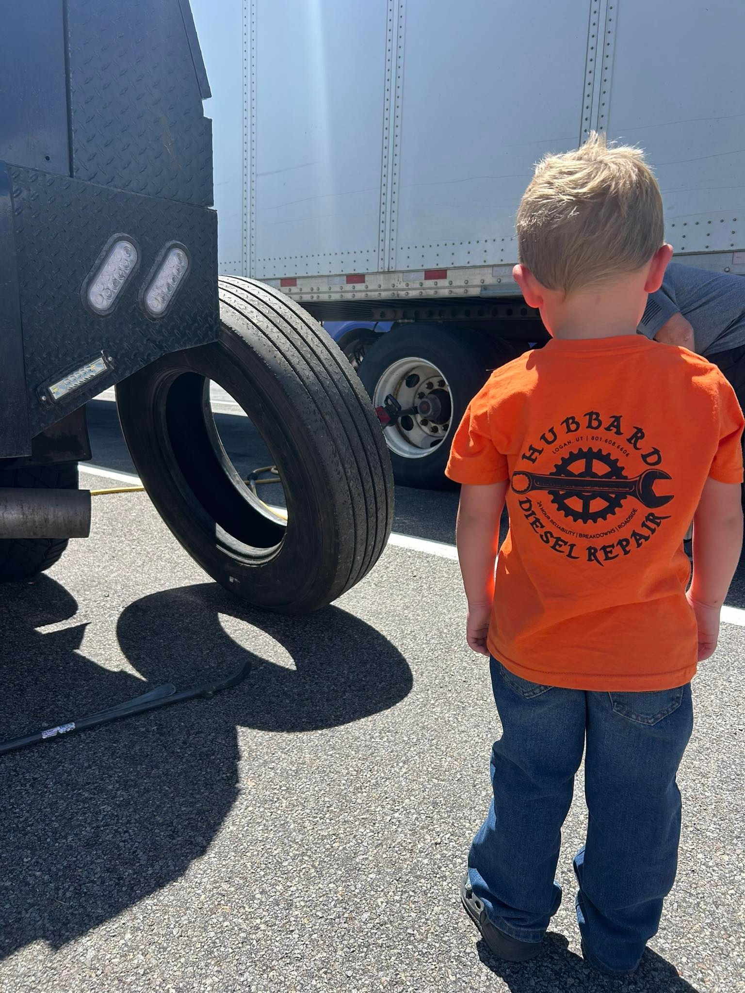 A young boy in an orange shirt that says 