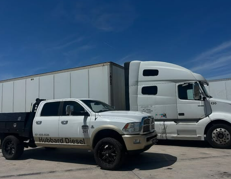 White pickup truck and semi-truck parked next to each other on a sunny day.