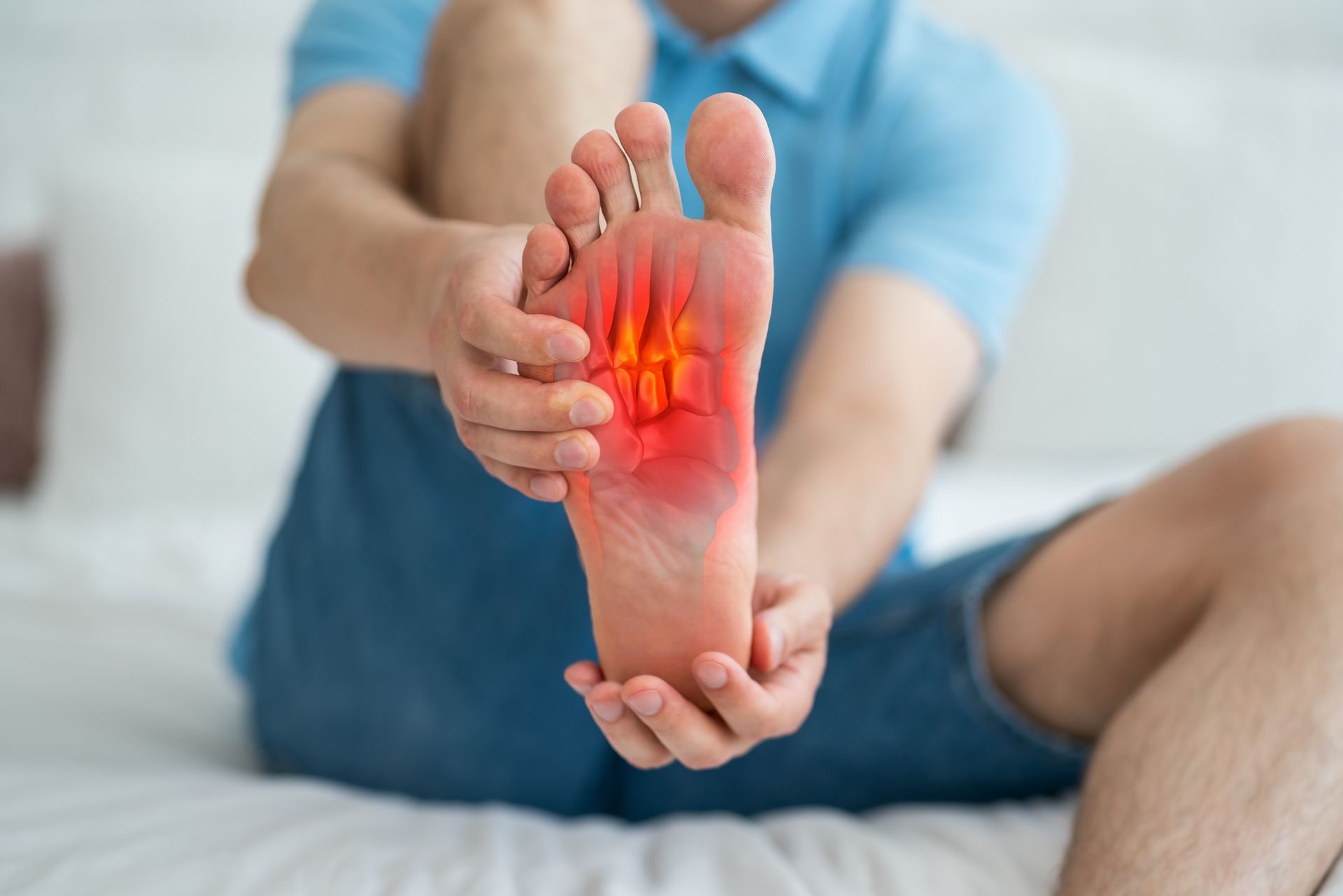 Man holding foot, highlighting red, painful area on sole, indicating foot pain.