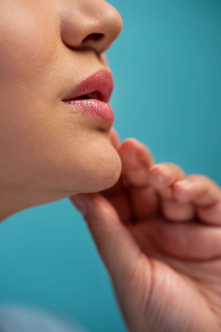 A close up of a woman 's face with her hand on her chin.