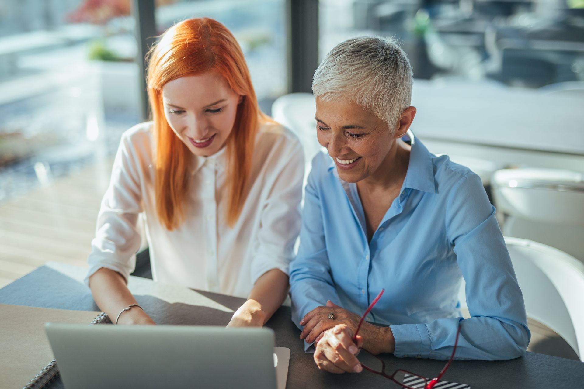 Business colleagues in suits discussing documents around a wooden table with a laptop.