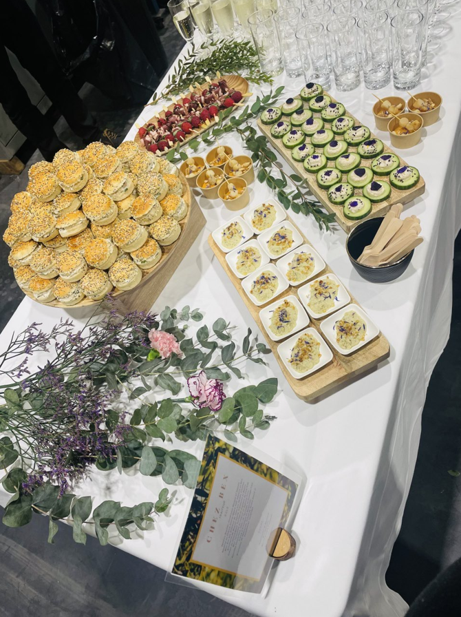 Buffet avec divers apéritifs, dont des scones, des tartes et des bouchées de concombre.