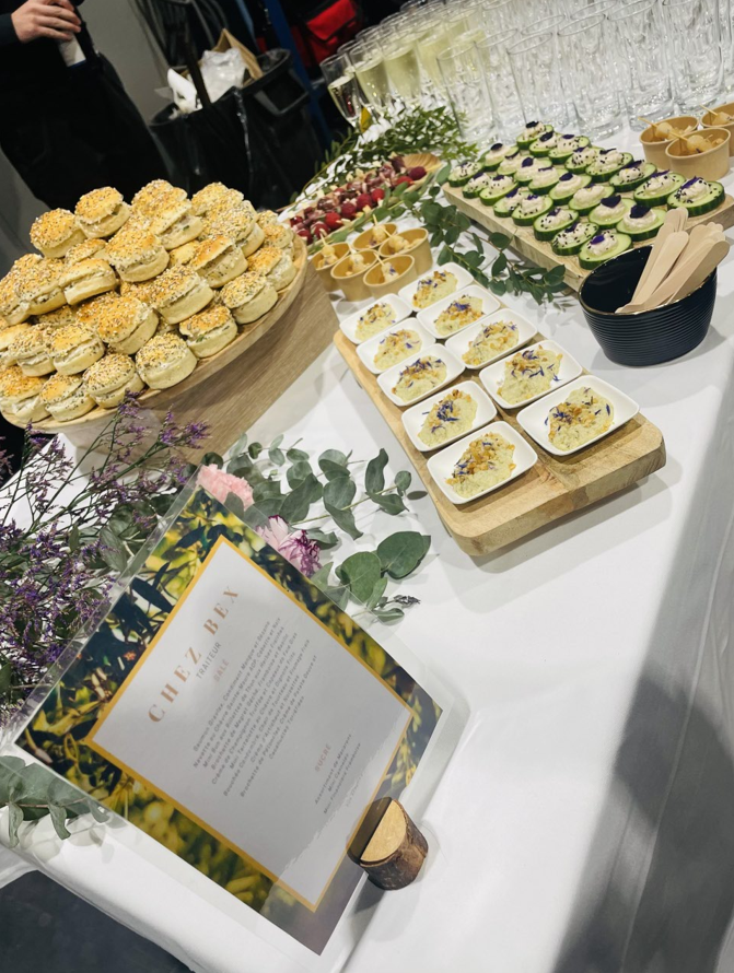 Buffet avec diverses entrées : mini sandwichs, bouchées de concombre et petites quiches.