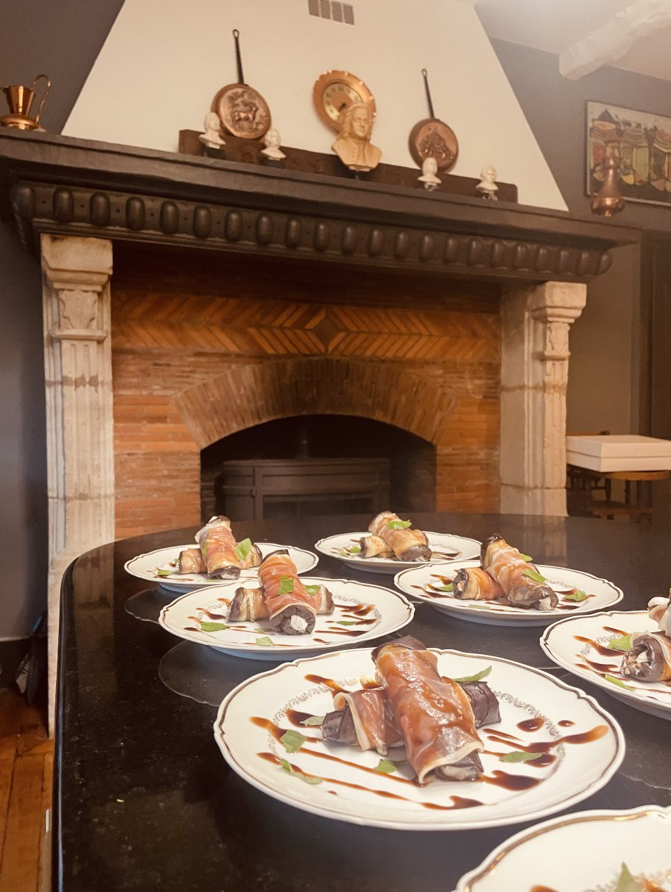 Plats servis sur une table avec une cheminée en arrière-plan. Chaque assiette est accompagnée d'un petit pain en sauce.