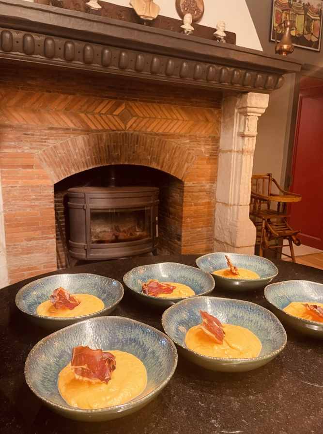 Des bols de polenta garnis de charcuterie disposés sur une table devant une cheminée en briques.