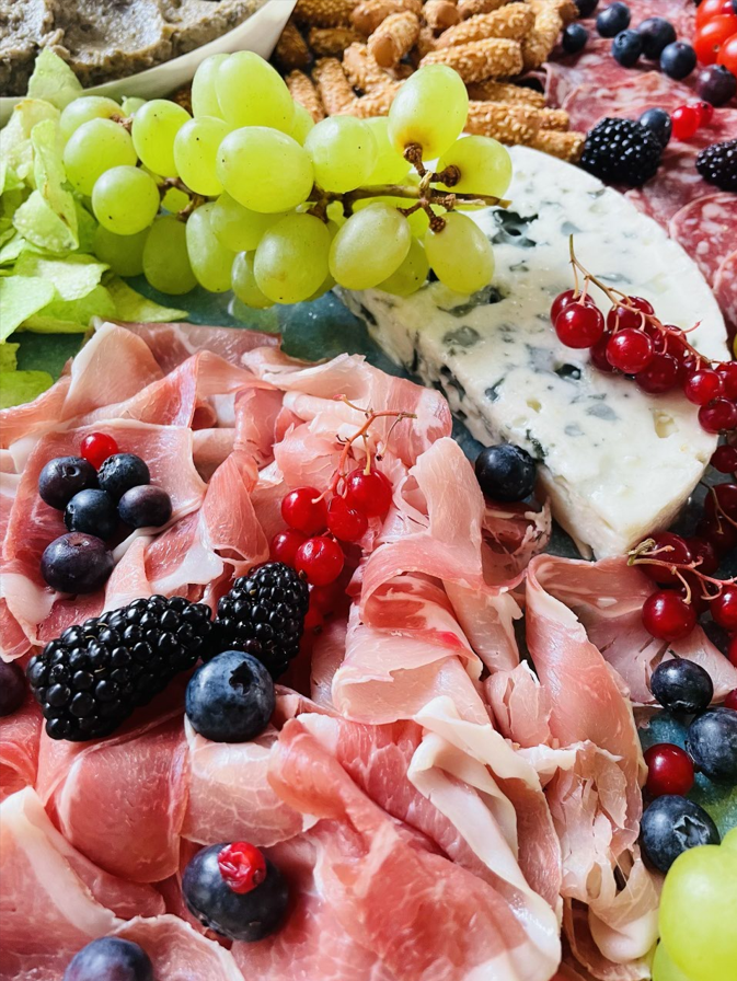 Planche de charcuterie avec raisins, prosciutto, baies, fromage bleu et craquelins.