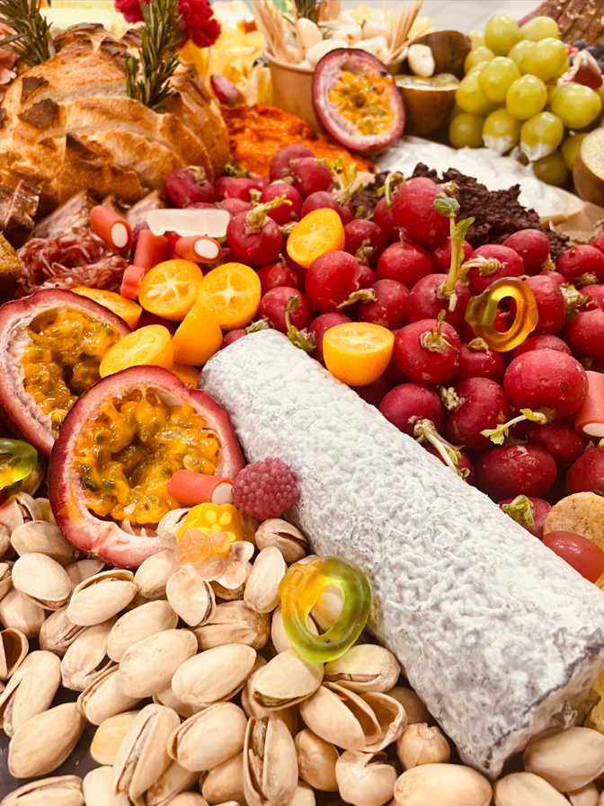 Planche de charcuterie avec pistaches, fruits, fromage et pain.