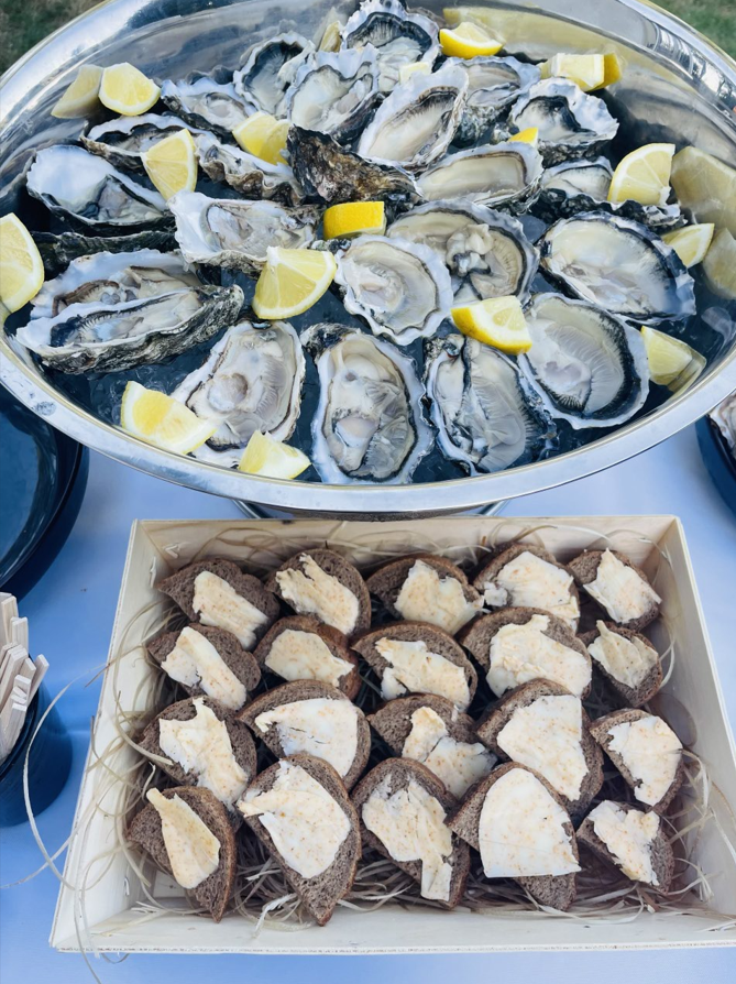 Huîtres sur glace avec des quartiers de citron au-dessus d'un plateau de pain de seigle avec du beurre.