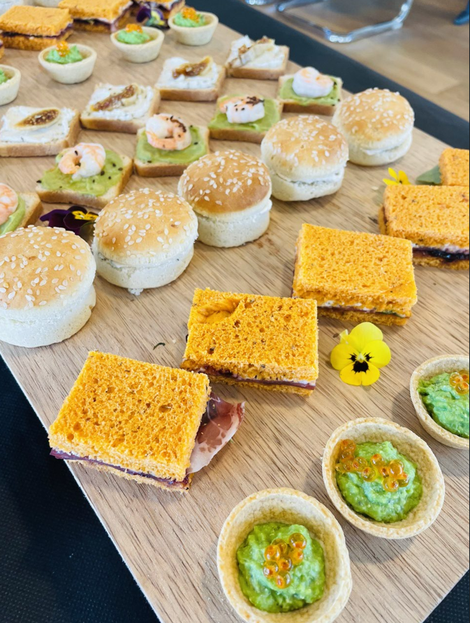 Assortiment de bouchées colorées sur une planche en bois. Mini-sandwichs, biscuits et tartelettes garnis de sauces.