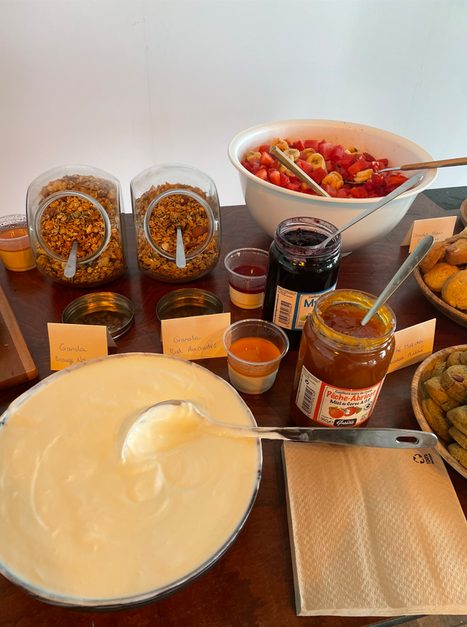 Buffet petit-déjeuner : yaourt, granola, baies, confitures, miel, muffins.