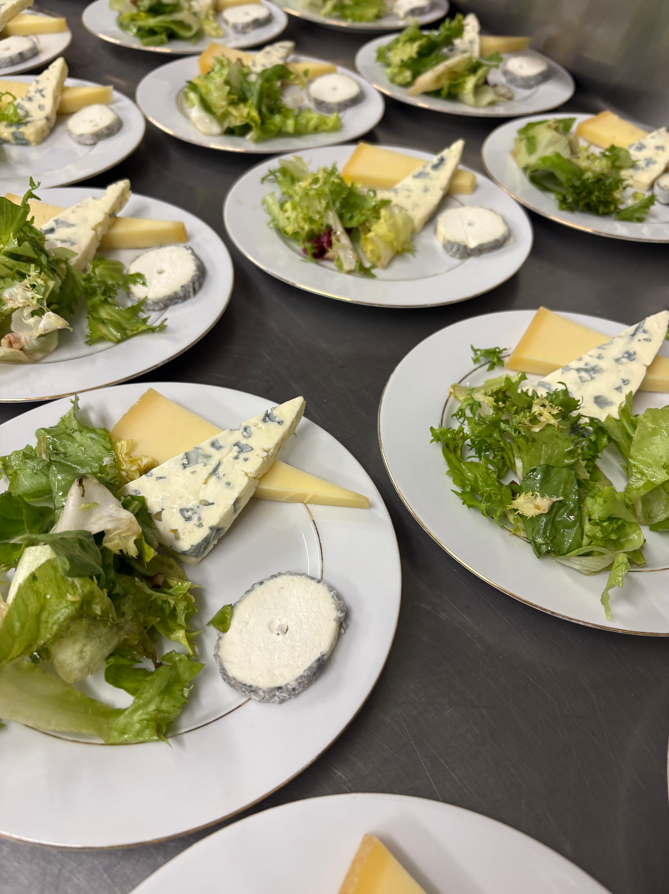 Assiettes de fromages, salade de laitue et fromage de chèvre disposés sur un comptoir.