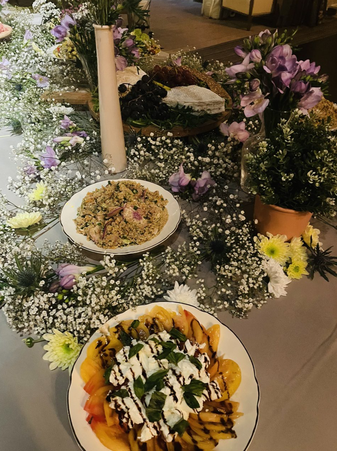 Décoration de table avec deux plats, entourés de compositions florales, dont des gypsophiles, sur une nappe grise.