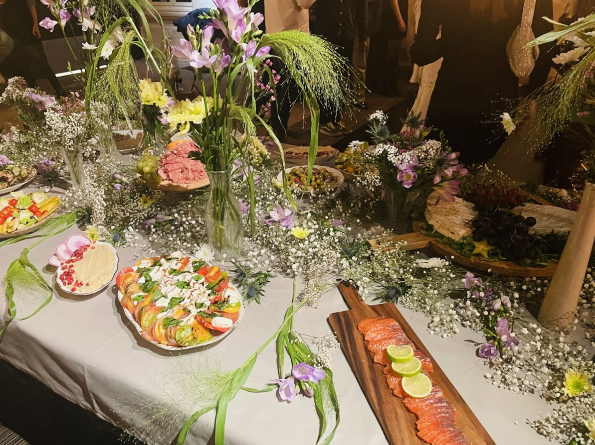 Table de buffet avec fruits et saumon, décorée de fleurs et de verdure.