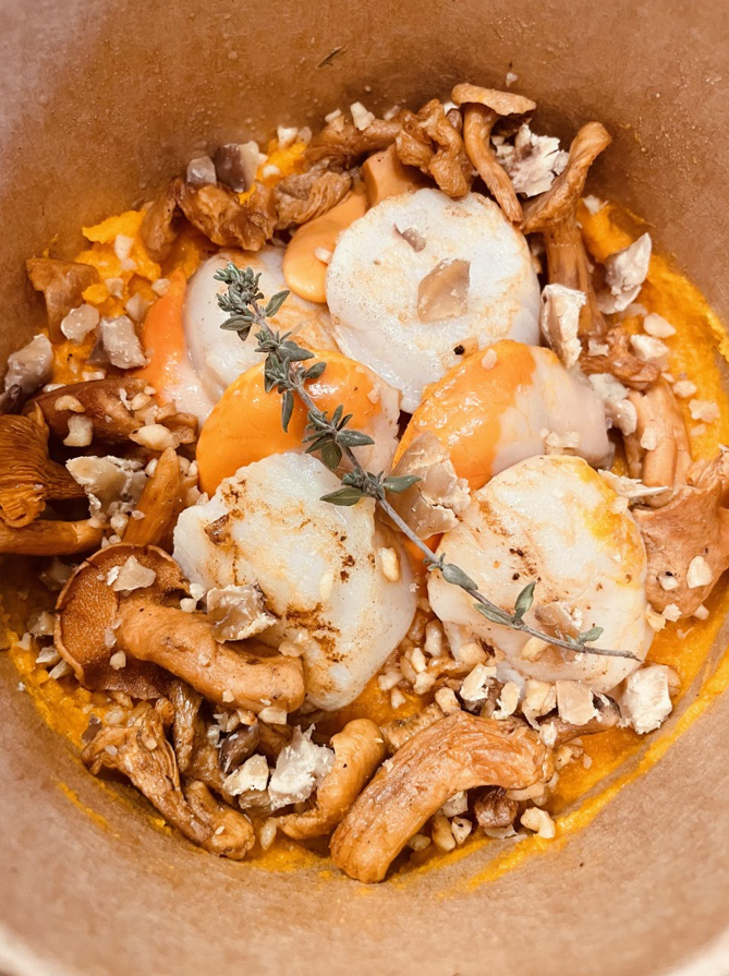 Pétoncles poêlés avec champignons, carottes et noix, dans un bol en papier.