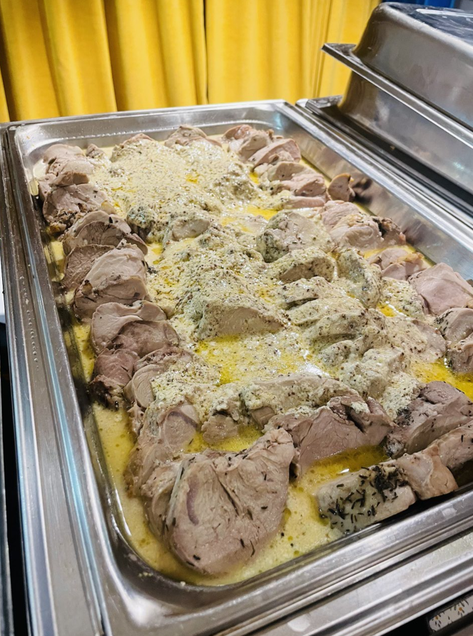 Plateau de viande tranchée dans une sauce crémeuse, probablement partie d'un buffet.
