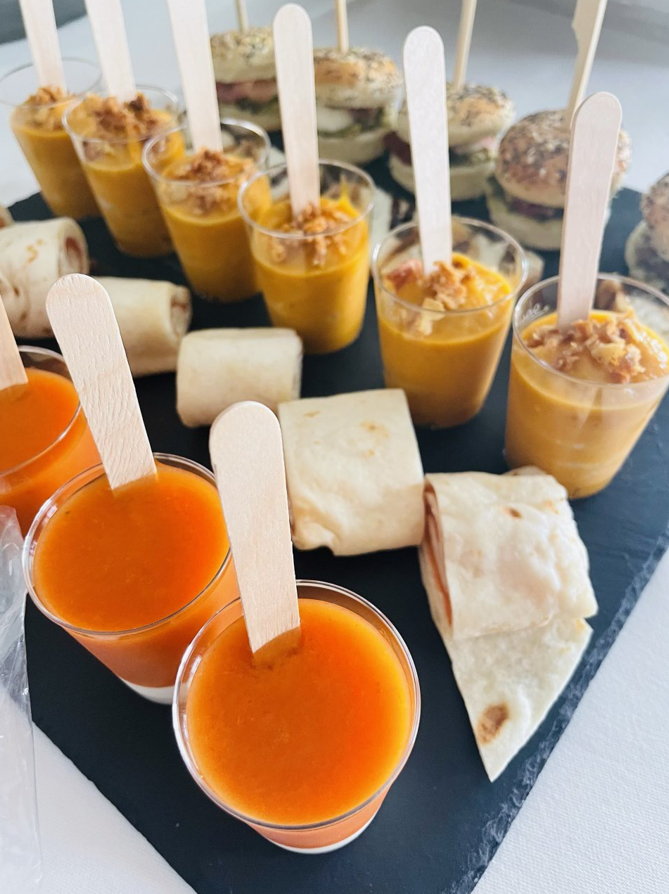 Entrées sur ardoise noire : petites tasses de soupe avec des cuillères en bois, mini sandwichs et aliments emballés.